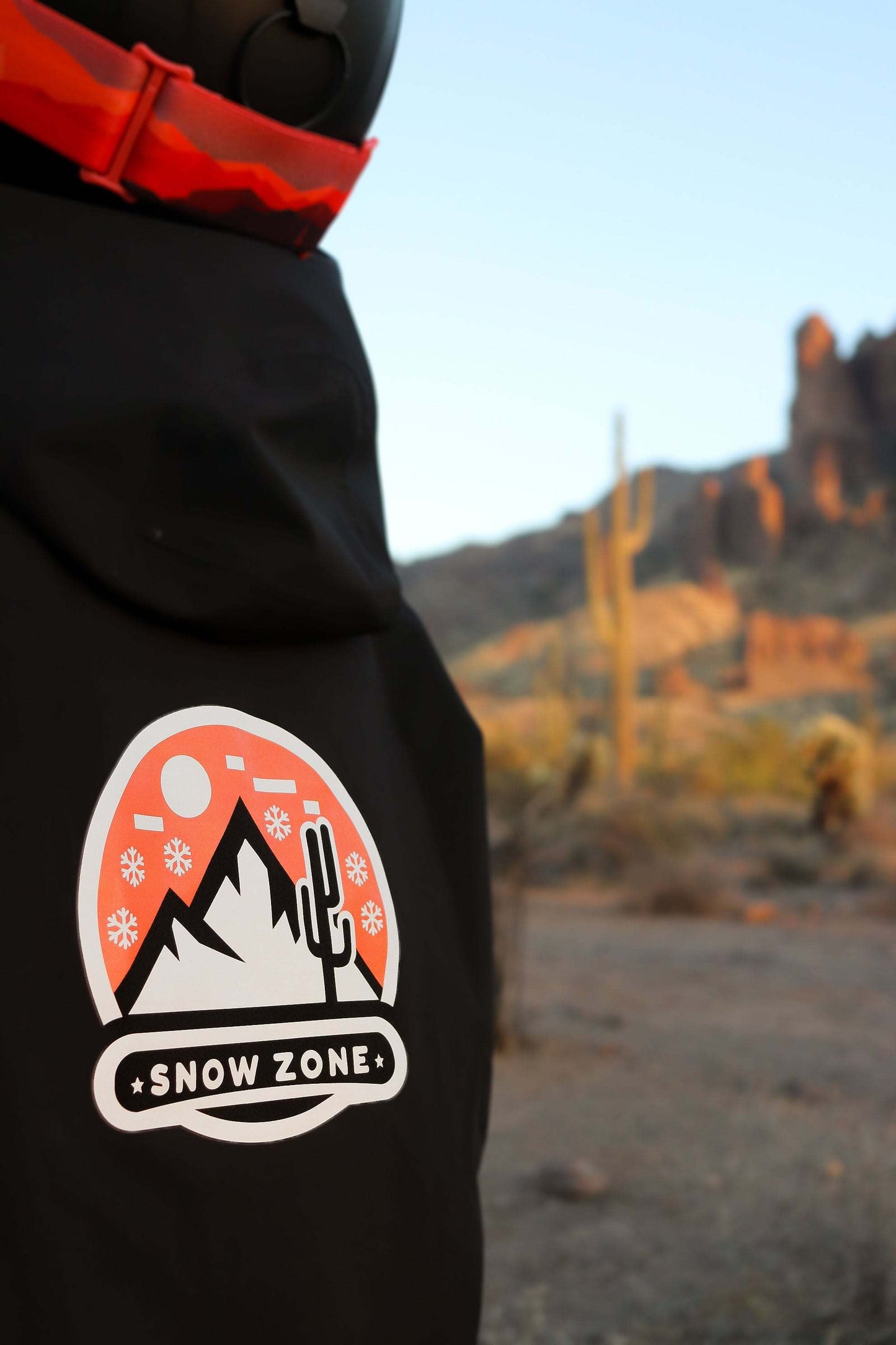Black insulated snow jacket with mountain and cactus snow zone logo near wrist pass holder and powder skirt features